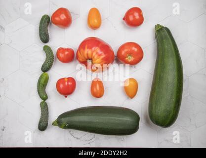 Ripe vegetables-tomatoes, zucchini and cucumbers are laid out on a light background. Stock Photo