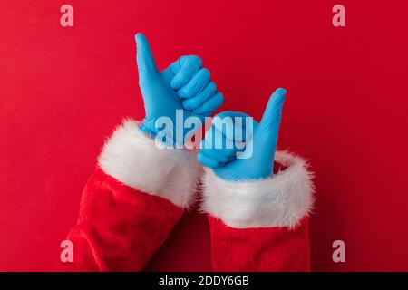 Santa hands wearing blue PPE protective gloves making thumbs up sign Stock Photo