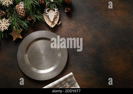 Christmas table place setting with natural decoration and metallic plate on brown table. View from above with copy space. Stock Photo