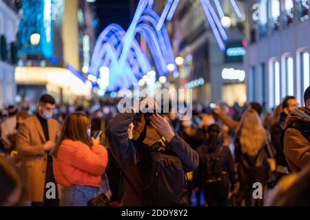 A man takes photos of Christmas lights at Puerta del Sol, Madrid's central square.Madrid officially starts the Christmas season by turning on 10.8 million LED lights throughout the capital. In total, there are more than 210 illuminated streets distributed throughout the 21 districts of the city of Madrid. The Community of Madrid proposed to the Spanish Ministry of Health a plan for Christmas, in which family and social gatherings are with a maximum of 10 people from three different groups of partners. Also on December 24, 25, 31 and January 1 and 6, a curfew at 1.30 am. Stock Photo