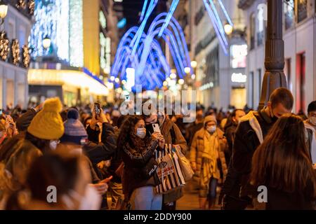 Crowds of people wearing masks gather at Puerta del Sol, Madrid's central square, waiting for the City Council to turn on the Christmas lights.Madrid officially starts the Christmas season by turning on 10.8 million LED lights throughout the capital. In total, there are more than 210 illuminated streets distributed throughout the 21 districts of the city of Madrid. The Community of Madrid proposed to the Spanish Ministry of Health a plan for Christmas, in which family and social gatherings are with a maximum of 10 people from three different groups of partners. Also on December 24, 25, 31 and Stock Photo