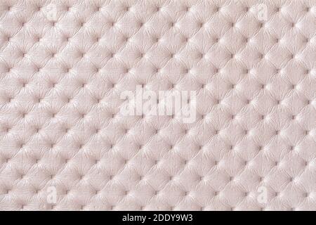 Texture of pearl beige leather background with capitone pattern, macro. Cream textile of retro Chesterfield style. Vintage fabric backdrop. Stock Photo