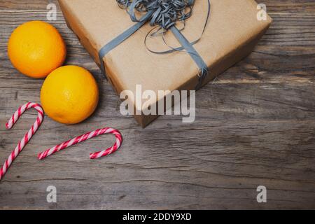 Saint Nicholas concept with brown gift box, oranges and striped candy canes on wooden background. Stock Photo