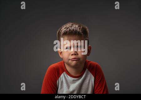 Little boy showing with his face I Dont Like It to his parents isolated on grey background. Fake child emotions. Facial expressions, emotions Stock Photo