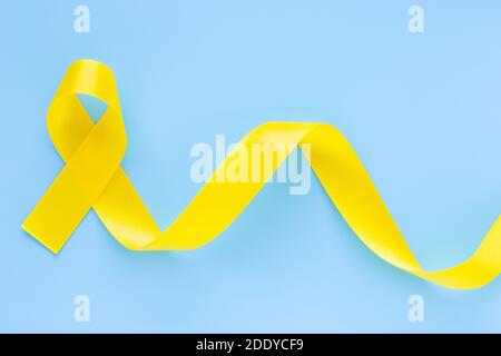 Yellow ribbon on light blue background, copy space. Bone cancer, Sarcoma Awareness, childhood cancer awareness, cholangiocarcinoma, gallbladder cancer Stock Photo