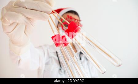 A woman doctor holds four test tubes on a white background. Stock Photo