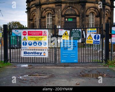 Brightly coloured construction site safety and social distancing signage on the gates of a closed United Utilities site. Stock Photo