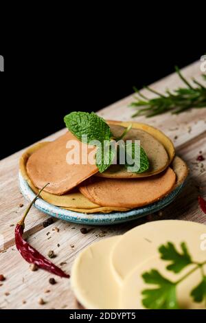 closeup of some slices of vegan cheese and some different cold cuts made of tofu on a white rustic table Stock Photo