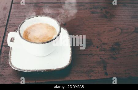 close-up view of cup of steaming hot italian espresso on red rustic wooden table Stock Photo