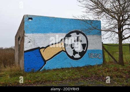 Glasgow, Scotland, UK. 27th, November, 2020. A piece of graffiti art paying tribute to Argentinian footballer Diego Maradona, who passed away, depicting the hand ball incident whilst scoring against England in a world cup game, appeared in Blackhill, Glasgow. The incident was later described as 'The hand of God' which is the subject of the art. Credit. Douglas Carr/ Alamy Live News Stock Photo