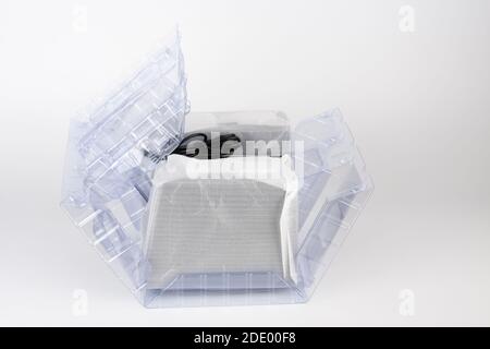 Two computer speakers in transparent plastic bag on white background. In the middle between the speakers is black box with AC adapter. Stock Photo