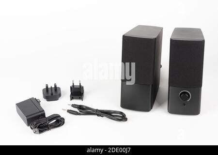 Two computer speakers on white background.  AC adapter with European plug and American plug  and audio cable. Stock Photo