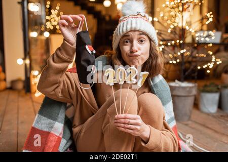 Portrait of a sad woman holding face mask during a celebration 2021 New Year holiday, hoping that the pandemic will end Stock Photo