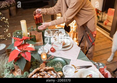 Woman serving and decorating a festive dinner table on the christmas eve outdoors on the terrace Stock Photo