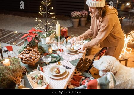 Woman serving and decorating a festive dinner table on the christmas eve outdoors on the terrace Stock Photo