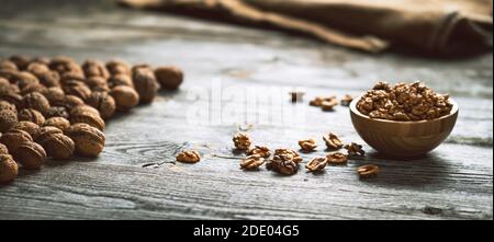 Fresh walnut kernels and whole walnuts in a bowl on rustic old wooden table. Healthy organic food, BIO viands, natural background. Copy space for your Stock Photo