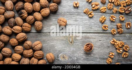 Heap of fresh walnut kernels and whole walnuts on wooden table - natural pattern background detail. Close up of brown surface texture. Healthy organic Stock Photo