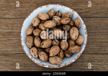 Top view of pecan nuts in a white bowl on wooden table Stock Photo