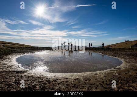 Small frozen lake for cows and a group of hikers on Lessinia Plateau, Regional Natural Park, Alps, Verona Province, Veneto, Italy, Europe. Stock Photo