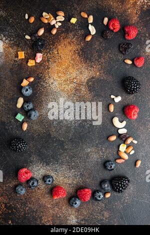 Frame made of mixed dried and raw ripe berry and fruits with nuts, top view with copy space, on old dark table Stock Photo