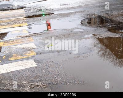 puddles from the first melted snow on pedestrian crossing in city in autumn Stock Photo