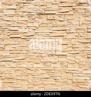 Beige stone wall with decorative masonry. Front view. Background texture Stock Photo