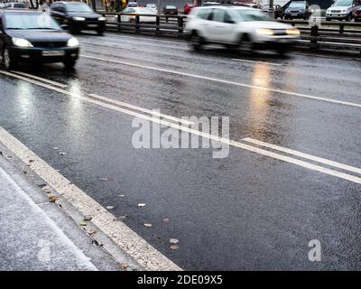 wet surface of city road and blurred in motion cars on autumn evening Stock Photo
