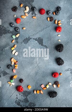 Frame made of mixed dried and raw ripe berry and fruits with nuts, top view with copy space, on grey background Stock Photo
