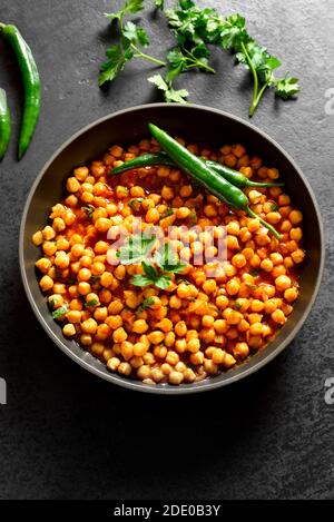 Crispy roasted chickpeas. Indian style dish over black stone background. Vegetarian vegan food concept. Stock Photo