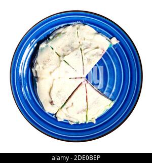 cooking sweet sponge cake at home - top view of cutted homemade sponge cake covered by whipped cream on blue plate cut out on white background Stock Photo