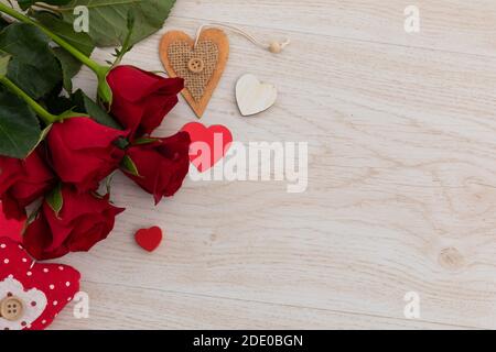 Bunch of red roses and hearts lying on wooden background Stock Photo