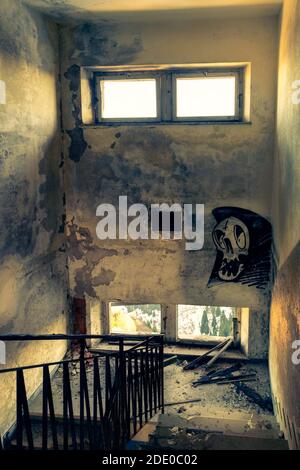 Destroyed stairway, moldy graffitied walls, window openings. Interior of an abandoned building in ruins. Monte Grappa, Vicenza, Italy Stock Photo