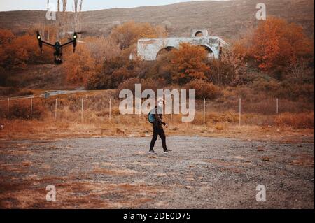 Young curly man trying to run away from drone security Stock Photo