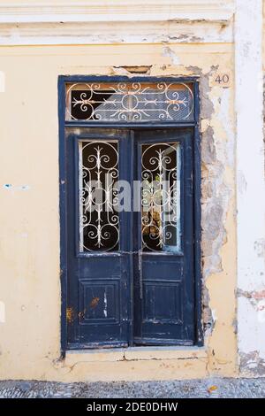 Old distressed blue painted wooden doors with ornate ironwork on facade of abandoned house, Old Town of Rhodes, Rhodes, Greece Stock Photo