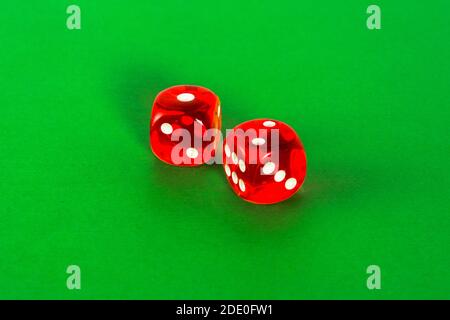 Red transparent dice for gambling on a green background. Stock Photo
