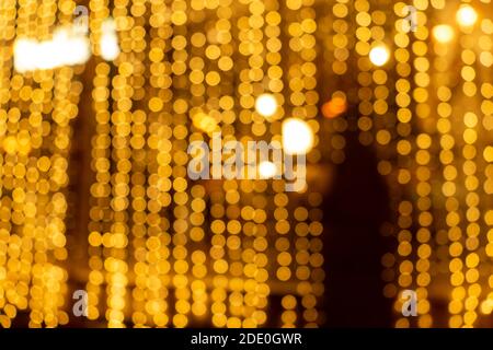 Cozy evening in the festive city. Blurred image of shop windows  decorated with light garlands for Christmas and New Year celebration. Shining window Stock Photo