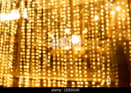 Cozy evening in the festive city. Blurred image of shop windows  decorated with light garlands for Christmas and New Year celebration. Shining window Stock Photo