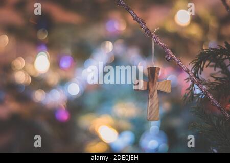 wooden cross symbol on glittering background of christmas tree lights Stock Photo