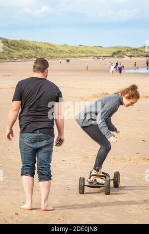 young couple having fun on long board kite surfing on Druridge Bay beach in Northumberland Stock Photo