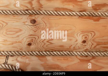 Wall of a wooden log house decorated with decorative rope. Wooden texture closeup Stock Photo