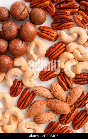 Pecans, brazil nuts, cashews, almonds and macadamia nut. Proper nutrition composition of assorted nuts pattern vertical photo for banner, article or packaging. Flat lay Stock Photo