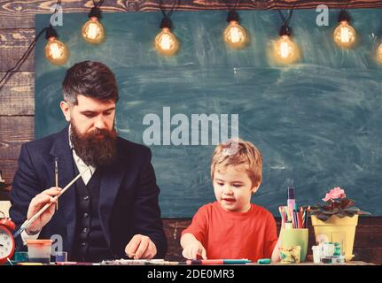 Daddy artist teaching his son how to paint. Blond kid learning to draw. Stock Photo