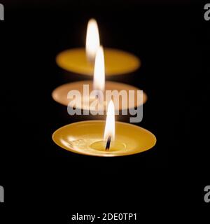 Three tea lights against a black background Stock Photo