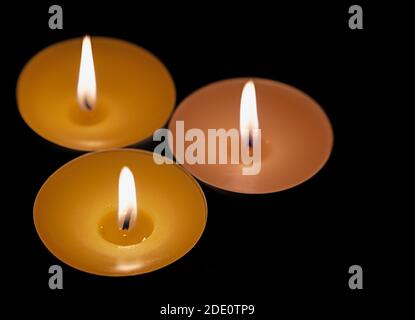 Three tea lights against a black background Stock Photo