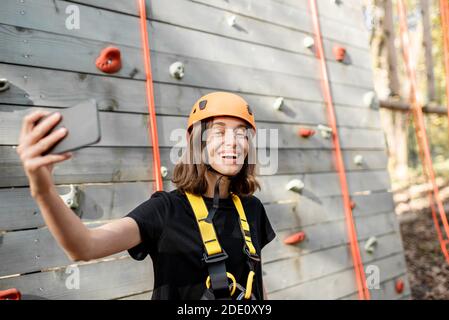 Young woman in protective sports equipment taking a selfie photo with a smart phone, young climber feeling happy in the park for sports entertainment Stock Photo