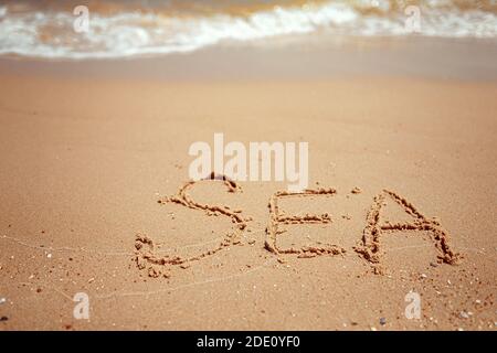 Handwritten Sea Word on the Sand Coast. Wonderful words on beach sand. Love idea concept. Stock Photo