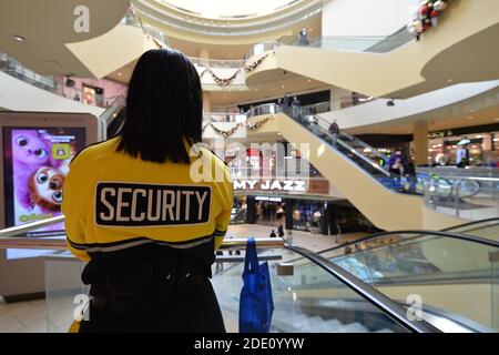 New York, USA. 27th Nov, 2020. A Queens Center Mall security guard keeps an eye on shoppers during Black Friday, in the Queens borough of New York City, NY, November 27, 2020. The CDC issued a warning against shopping in large crowds as a surge of Coronavirus cases grips the United States, which added two million people to the growing number of people infected with COVID-19. (Anthony Behar/Sipa USA) Credit: Sipa USA/Alamy Live News Stock Photo