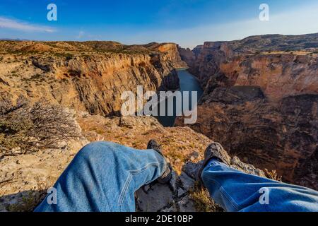 Dramatic overlook of Bighorn Canyon, with hiker's legs, from Sullivan's Knob Trail in Bighorn Canyon National Recreation Area, near Lovell, Wyoming, U Stock Photo