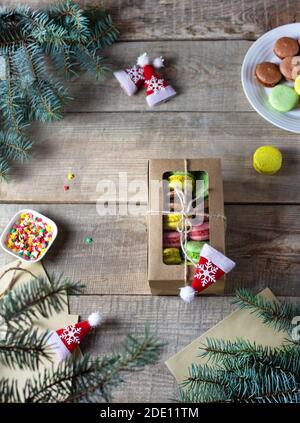 Colorful french macaroon cakes. Macaroon on a wooden background. Traditional macaroons on a Christmas background. Branches of a Christmas tree. Gift. Stock Photo