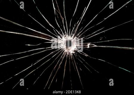 A bullet hole in glass. The background is black. Stock Photo